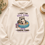 Beige hoodie with a raccoon graphic and text on a neutral background